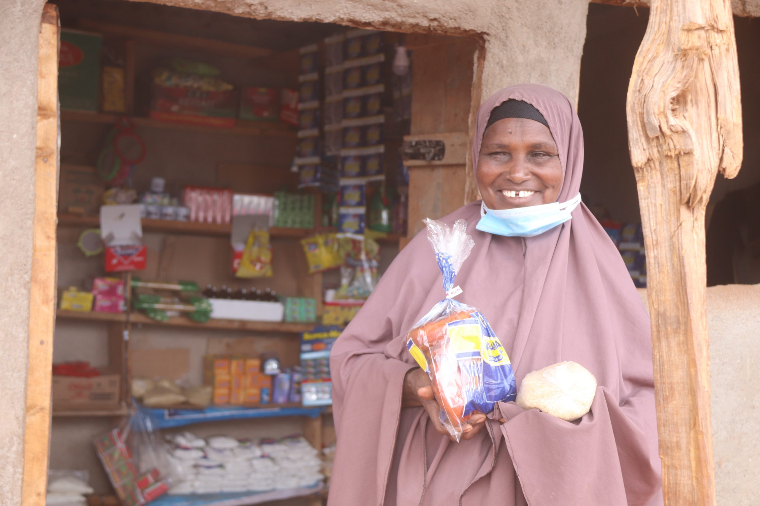 Photo/PACIDA: Halima Adan standing in front of her provision shop. She was given a business starter kit of Ksh.15, 000 from PACIDA through Kinisa Village Savings and Loans Association (VSLA) which she used to start her business.